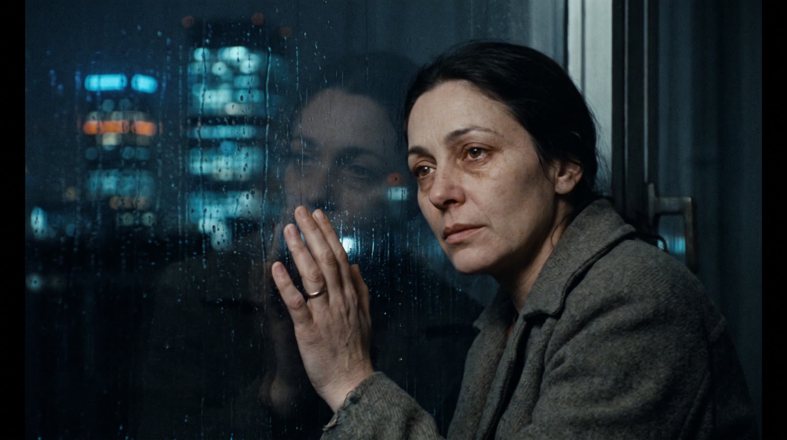 A small business owner at a rain-streaked window, city towers behind her